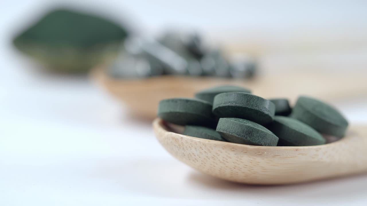 Close-up of Green Spirulina Pills in Wooden Spoon