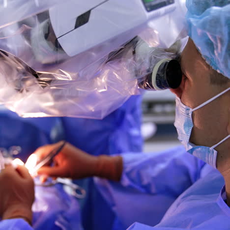 neurosurgeon carefully applies tools looking at microscope. surgical procedure in hospital. top view.