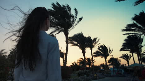 una chica bonita caminando en un jardín exótico. una mujer joven relajándose bajo las palmeras.