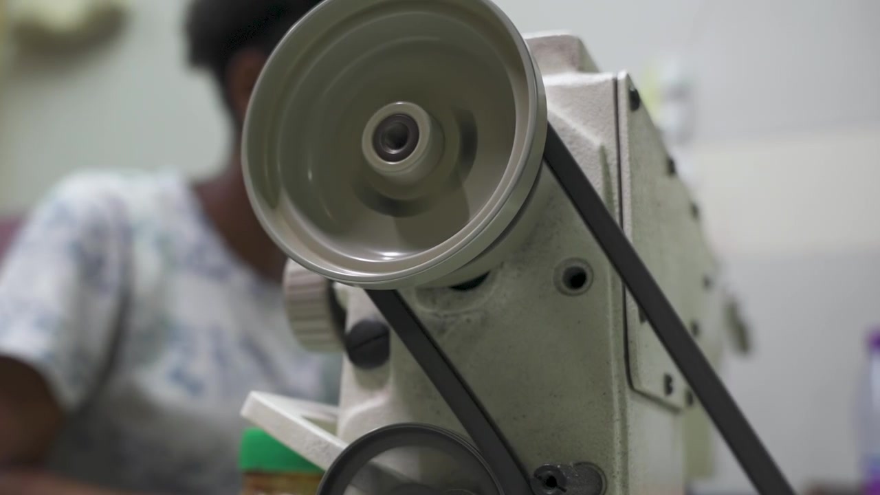 Close up of employee operating a sewing machine in workshop, focusing on the machine's mechanics. Suitable for industrial or craftsmanship content.