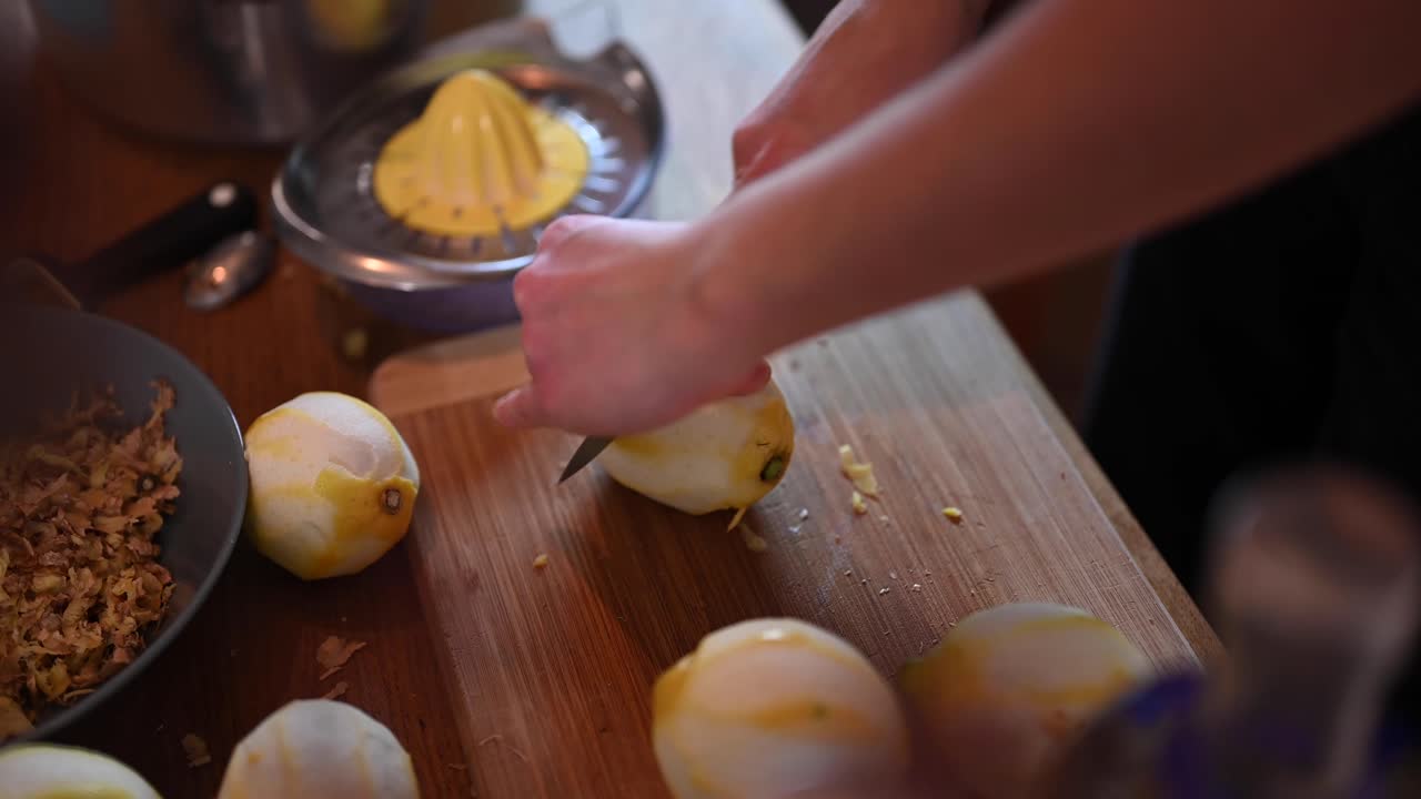 A stationary shot of a woman's hand rolling a peeled lemon against the table and slicing it in half