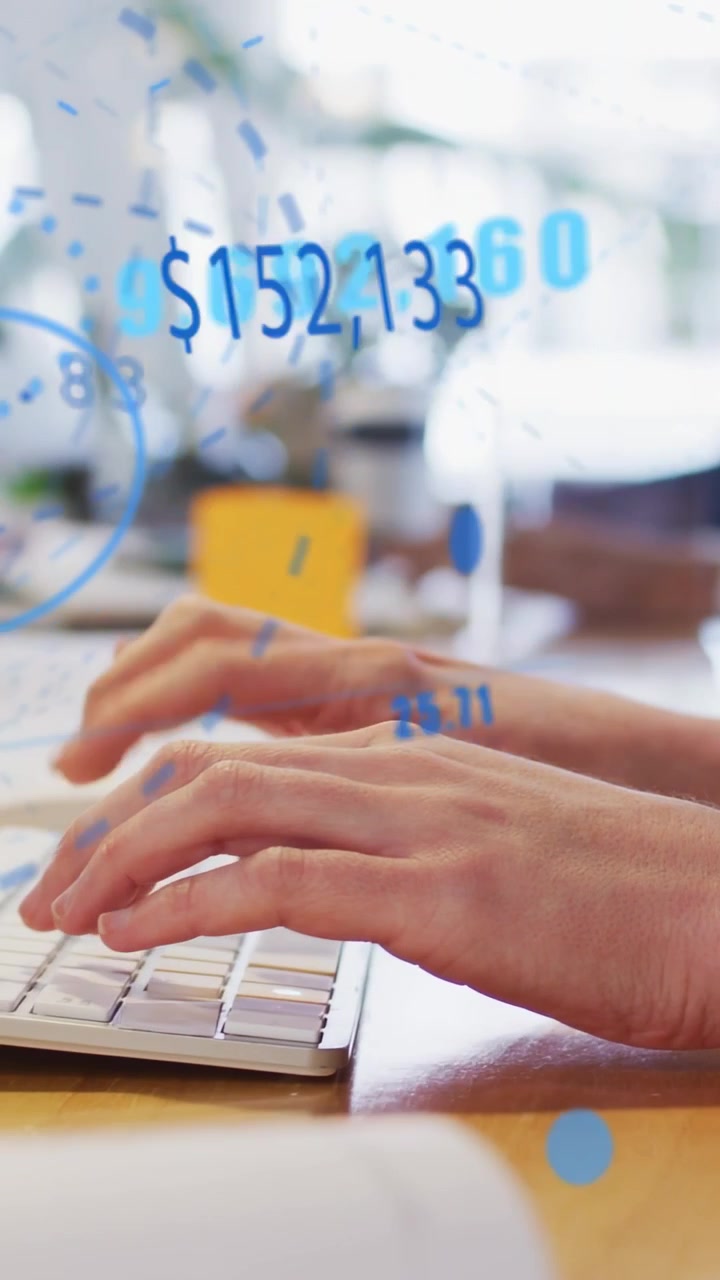 Video vertical: Manos de adulto escribiendo en un teclado compacto sobre un escritorio de madera, actualizando superposiciones financieras azules.
