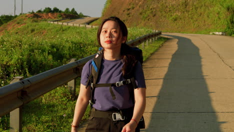 young woman backpacker looks confidently over into the golden sunset contemplating her journey