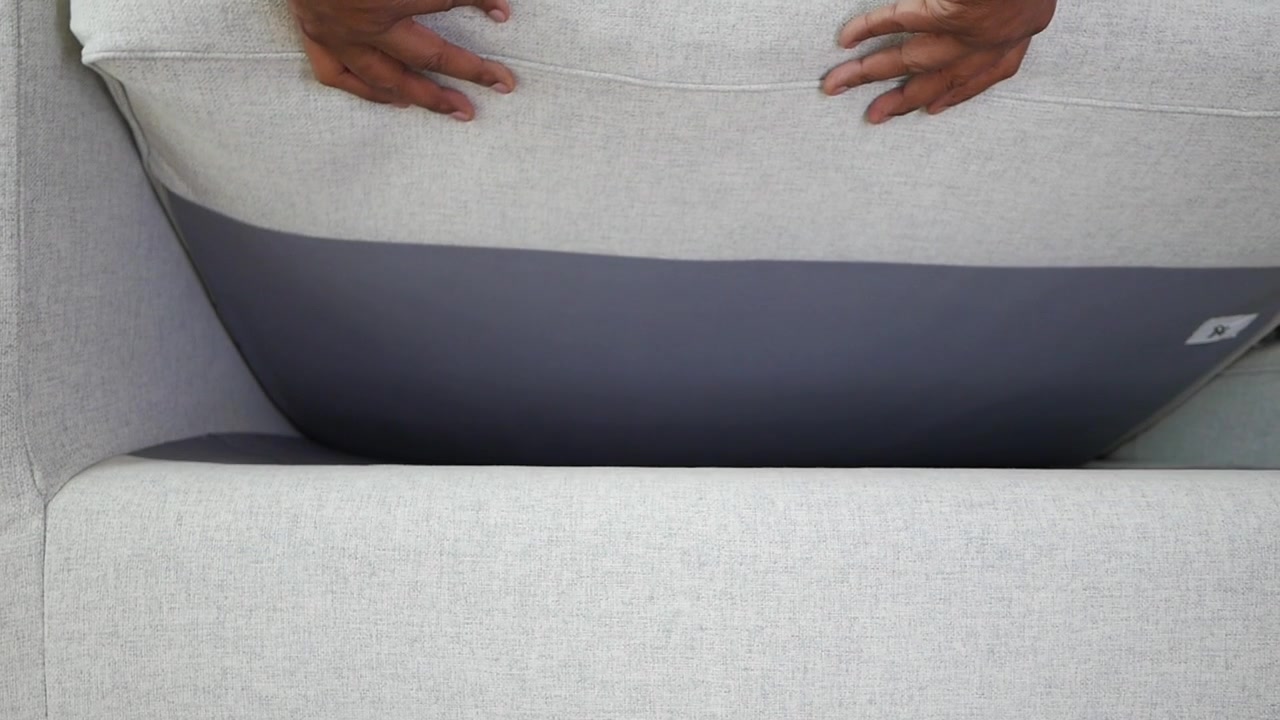 Person Adjusting and Smoothing Sofa Cushion in Living Room