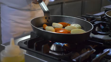 a chef in the kichten cooking and mixing peppers with a big flame, close up