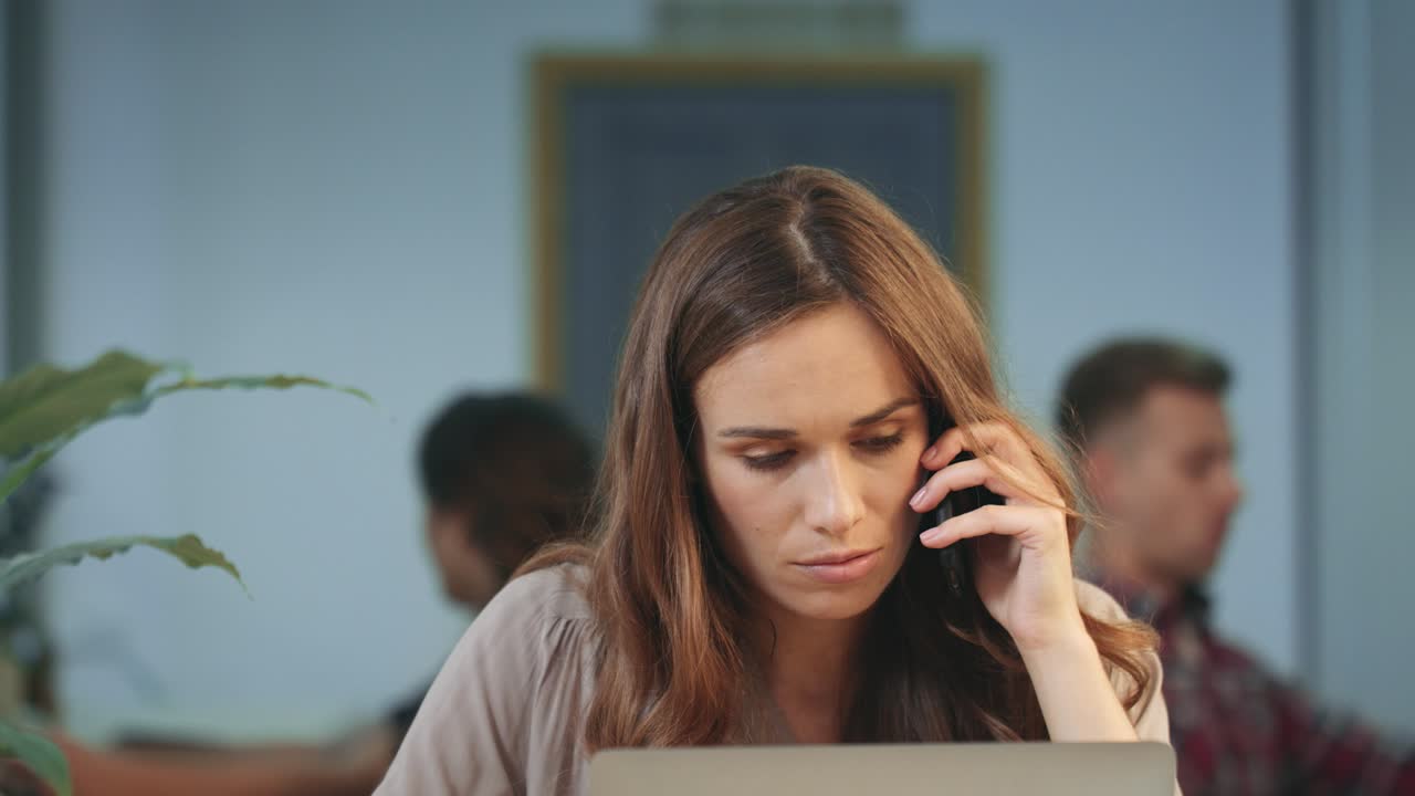 Unhappy business woman talking on mobile phone at coworking space. Angry woman
