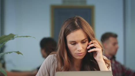 Unhappy-business-woman-talking-on-mobile-phone-at-coworking-space.-Angry-woman