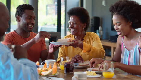 Family-Shot-With-Senior-Parents-And-Adult-Offspring-At-Breakfast-Around-Table-At-Home