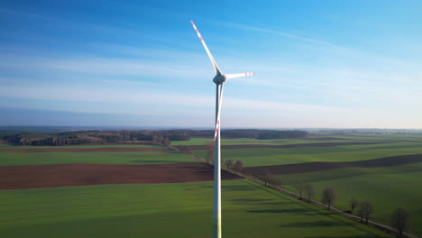 wind turbine against blue sky in rural farm - drone shot