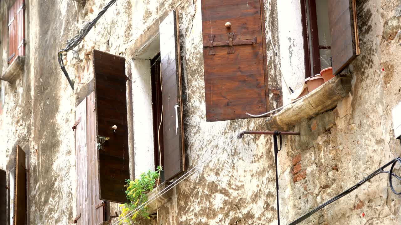 Una vista in lontananza del vecchio e storico muro con finestre e persiane sotto il sole estivo