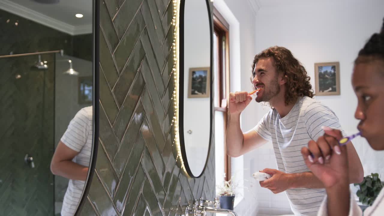 Giovane uomo caucasico si lava i denti in un bagno moderno.