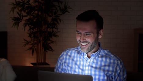 hombre juguetón usando una computadora portátil por la noche