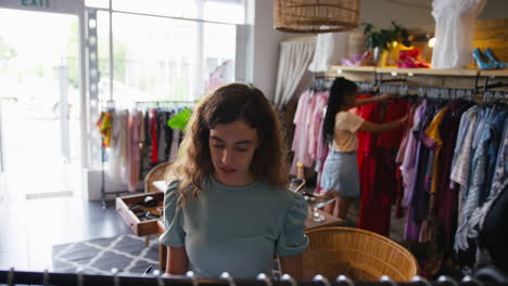 female owner or worker in fashion clothing store checking stock with clipboard