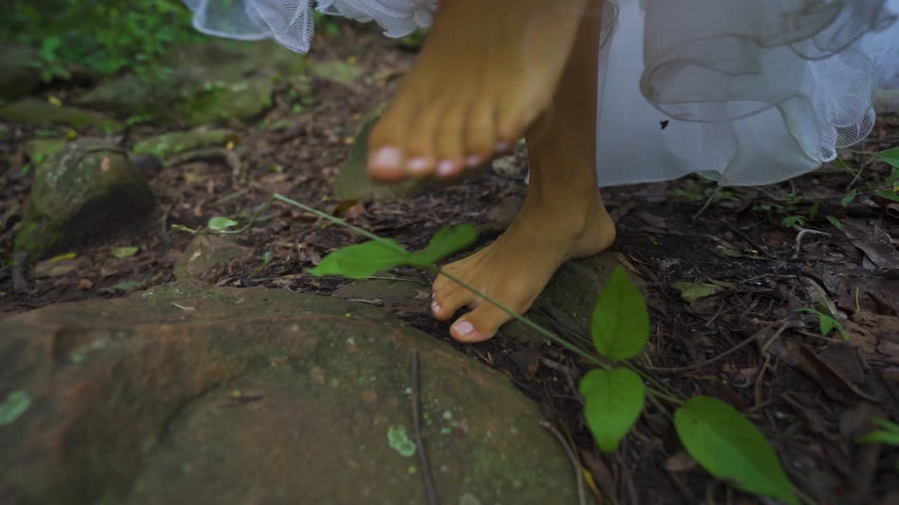 Female feet walking on the earth and stones in the jungle