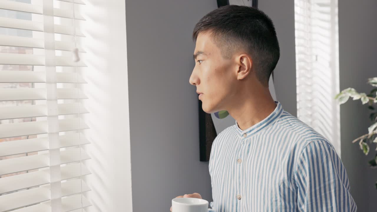 집중적이고 사려 깊은 직원, 사업가는 회사 사무실에서 창문 에 서서 장막으로 여 있고, 그것을 바라보고, 사업을 고려하고, 카메라에 미소 짓고 있습니다.