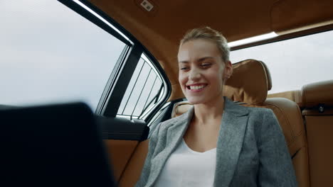 Successful-businesswoman-enjoying-success-in-car.-Business-woman-looking-laptop