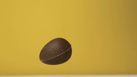 chocolate easter egg falling against yellow background