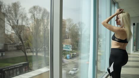 woman in fitness wear looking thoughtfully out window a woman in stylish fitness attire gazes thoughtfully out the window capturing a serene moment of introspection