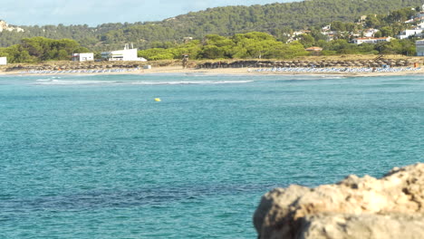 distant view of son bou beach in the early morning with empty beach beds, clear and transparent water, manorca, balearic islands, spain