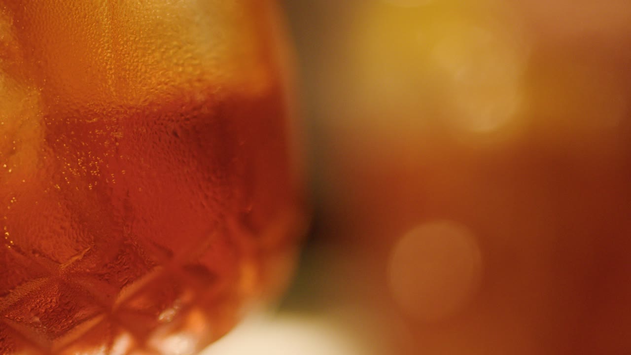 La fotocamera sposta la messa a fuoco da un bicchiere da cocktail dettagliato a uno sfondo sfocato in una calda e soffusa illuminazione da bar