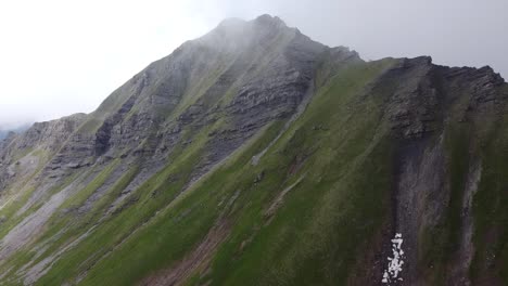 Drone-Shot-revealing-a-Dark-Mountain-through-the-Clouds