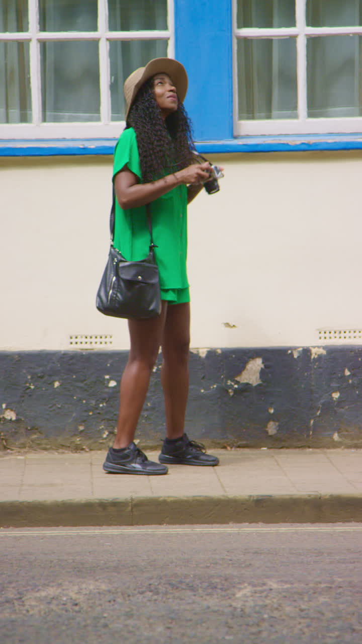 video vertical de una turista con cámara de vacaciones en oxford, reino unido, explorando la ciudad, caminando por la calle holywell tomando fotos.