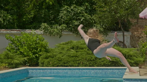 girl in black swimming costume loses balance and falls into swimming pool in slow motion