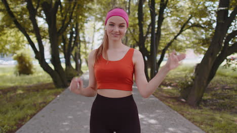 Athletic-fitness-runner-girl-waving-hi-hello-with-her-palm-greeting-with-hospitable-friendly-smile