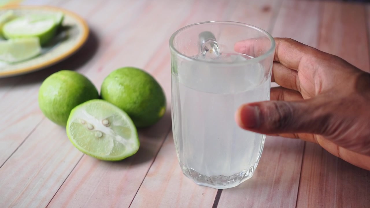 Hånd der tager et glas frisk limesaft