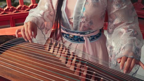 una chica china jugando al guzheng afuera.