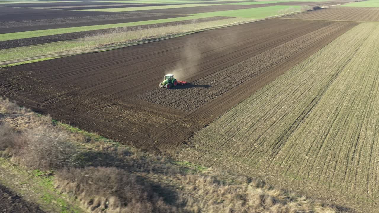 농경지, 농지 위에 씨 재배자를 끌고 다니는 트랙터의 공중 측면 이동 시각