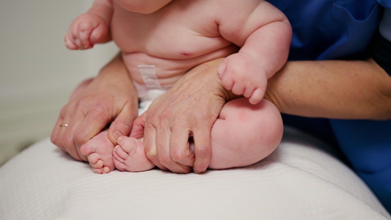 Baby placed on a stability ball while adults support the infant's body