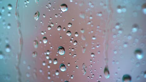 big raindrops on glass window background. slow motion of water drops flowing on the glass in a rainy weather. macro shot.