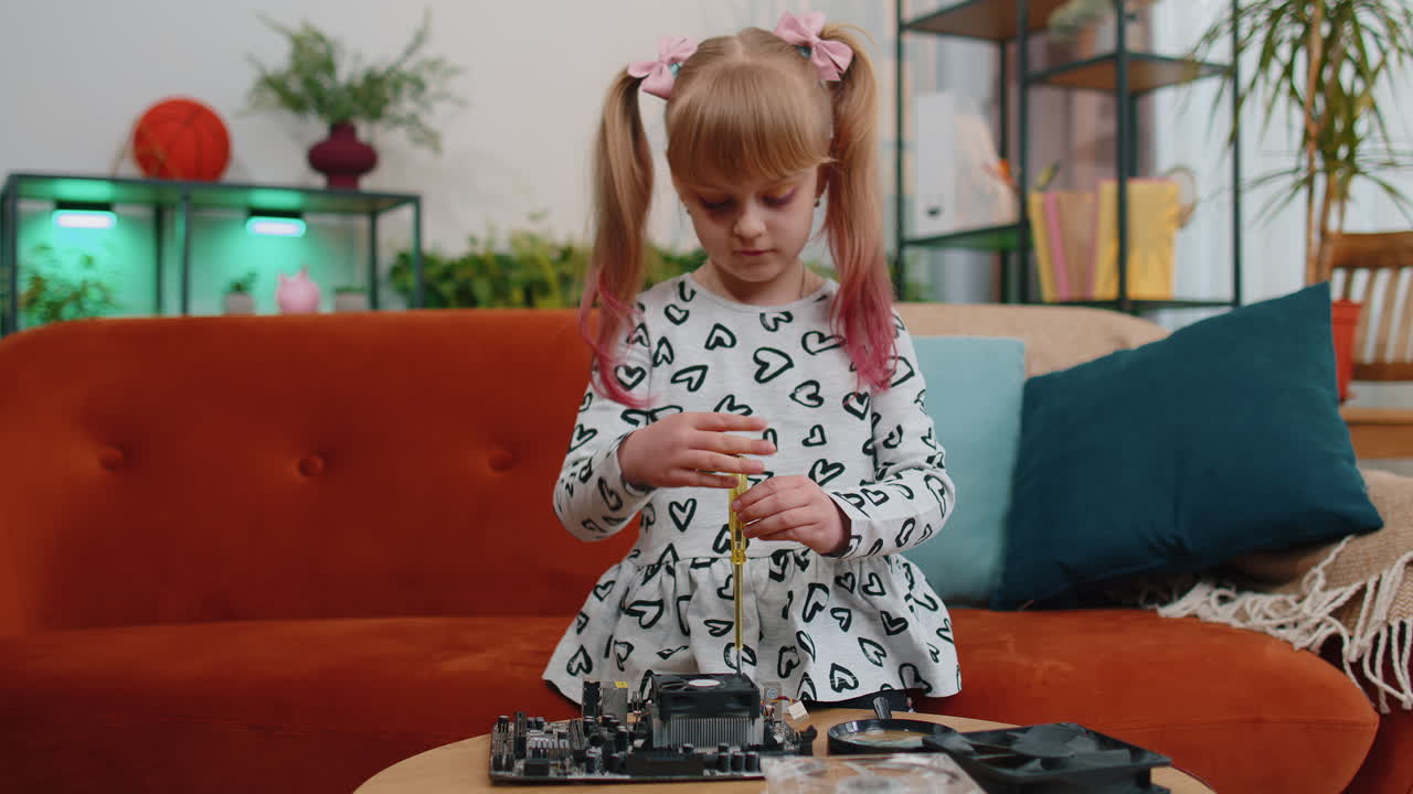 Piccola ragazzina intelligente con un cacciavite ripara la scheda madre del computer ventilatore elettronico a casa