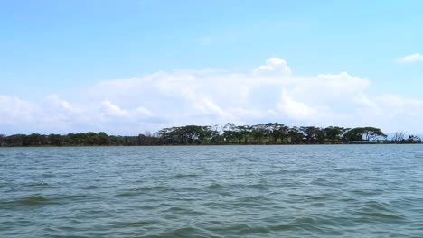 Cruising-with-a-motorboat-on-the-water-passing-by-a-white-butterfly-with-an-island-in-the-background