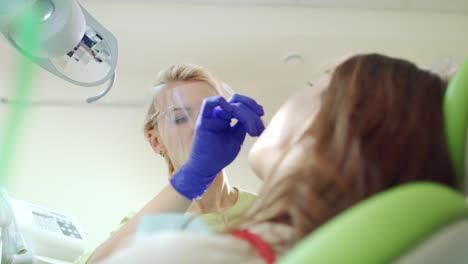 female dentist putting cotton tampon into open patient mouth. treatment process