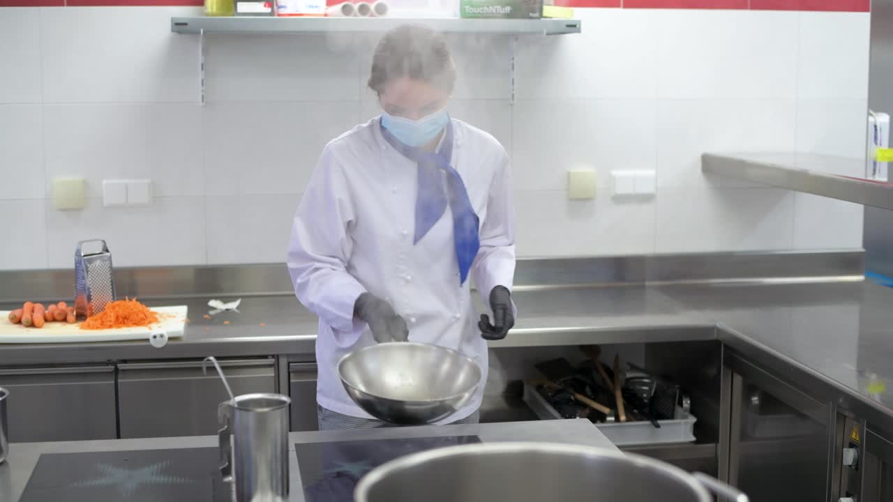 Premium stock video - Chef with face mask is cooking a meal in a hotel ...