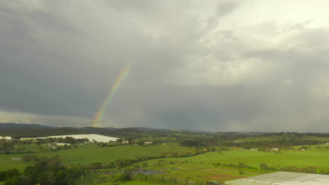 La-Perspectiva-Aérea-Se-Desplaza-Suavemente-Hacia-La-Derecha,-Revelando-Un-Pintoresco-Paisaje-Natural-Debajo-De-Un-Vibrante-Arco-Iris.