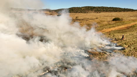 Aerial pan among rising smoke from fires during planned burn on dry farm field