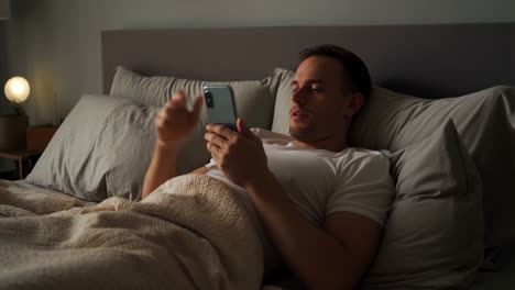 man relaxing in bed with phone
