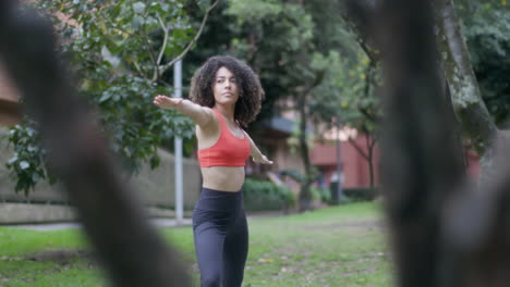 Dama-De-Cabello-Rizado-Que-Se-Extiende-Al-Borde-Del-Parque-Con-Un-árbol-En-Primer-Plano