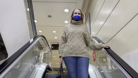 woman in medical mask getting downstairs by escalator in trade centre