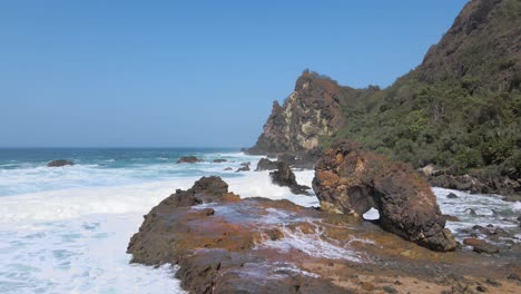 Aerial-drone's-forward-view-of-rocky-coastline-hit-by-waves