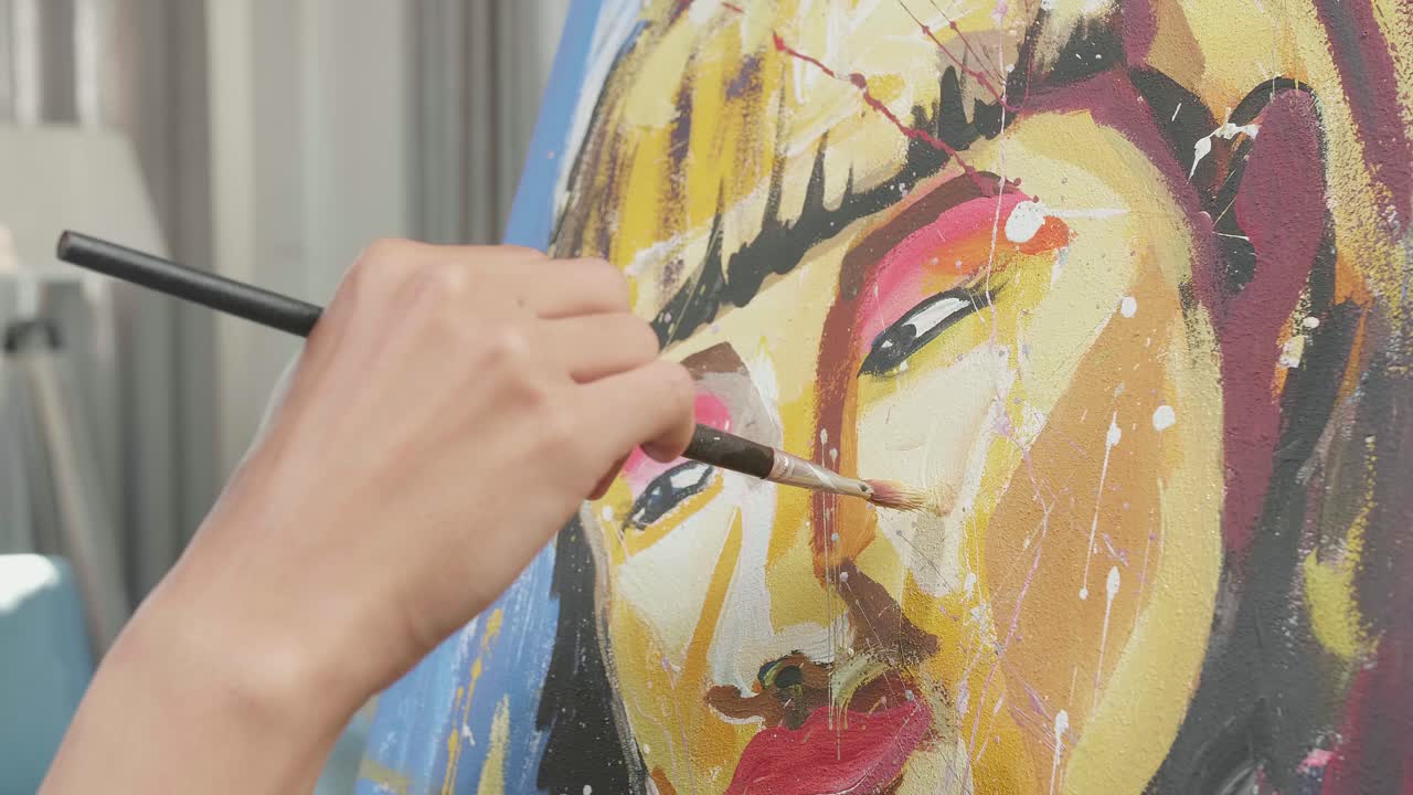 Close Up Of A Hand Holding Paintbrush Mixed Colour And Painting A Girl'S Face On The Canvas