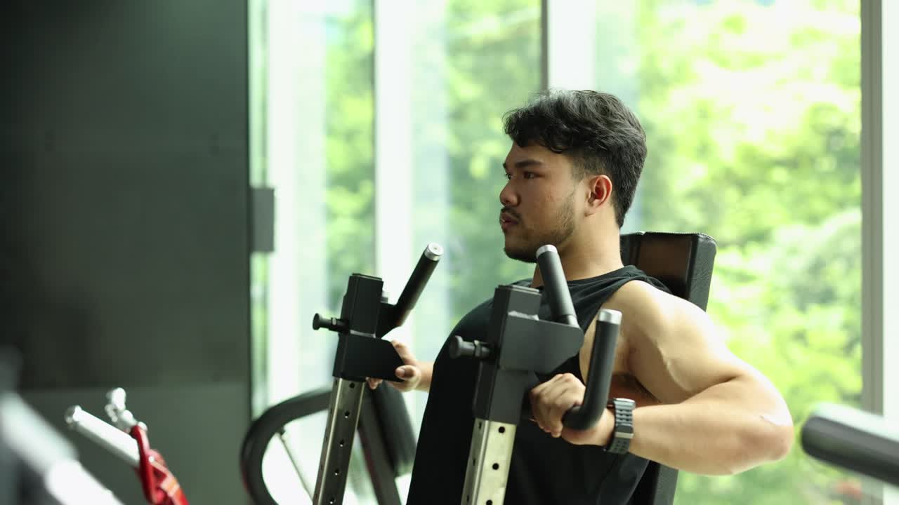 Focused man performing chest press exercise on machine in a bright, modern gym environment