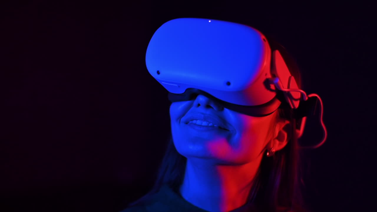 A young woman is excited while wearing VR glasses, Red and blue illumination. Slow motion