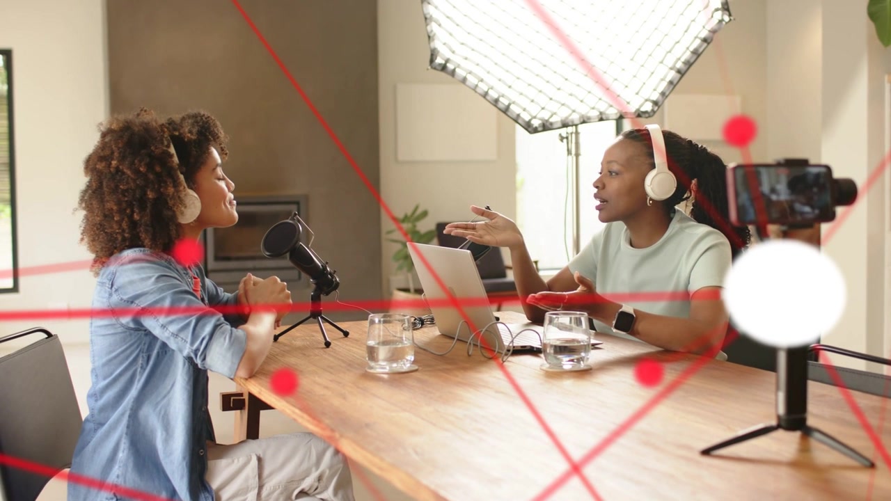 Apresentador da esquerda falando no microfone, causando uma sobreposição de grade vermelha na cena, e coapresentador gesticulando, podcasting