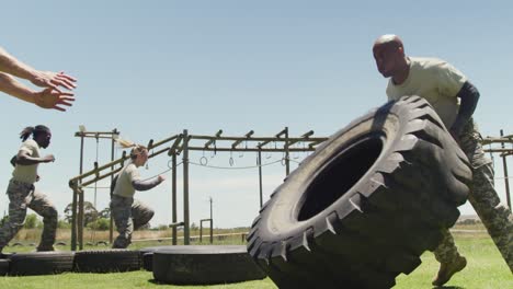 Colocar-Soldado-Afroamericano-Volteando-El-Neumático-Del-Tractor-En-La-Carrera-De-Obstáculos-Del-Ejército-Bajo-El-Sol