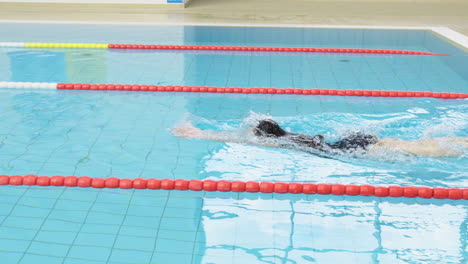 Weibliche-Junge-Schwimmerin-In-Zeitlupe-Im-Badeanzug,-Allein-Schwimmend-Im-Großen-Innenpool,-Trainingsübungen,-Gesunde-Fitness,-Sportliches-Tauchen-Im-Wasser