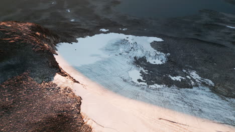 Revealing-aerial-of-lake-in-the-mountains-and-hills-landscape,-melting-snow-is-forming-the-lake-in-the-valley,-capture-location-Norway,-4K